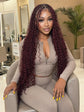 Woman with long burgundy box braids and curly extensions sitting in modern hair salon