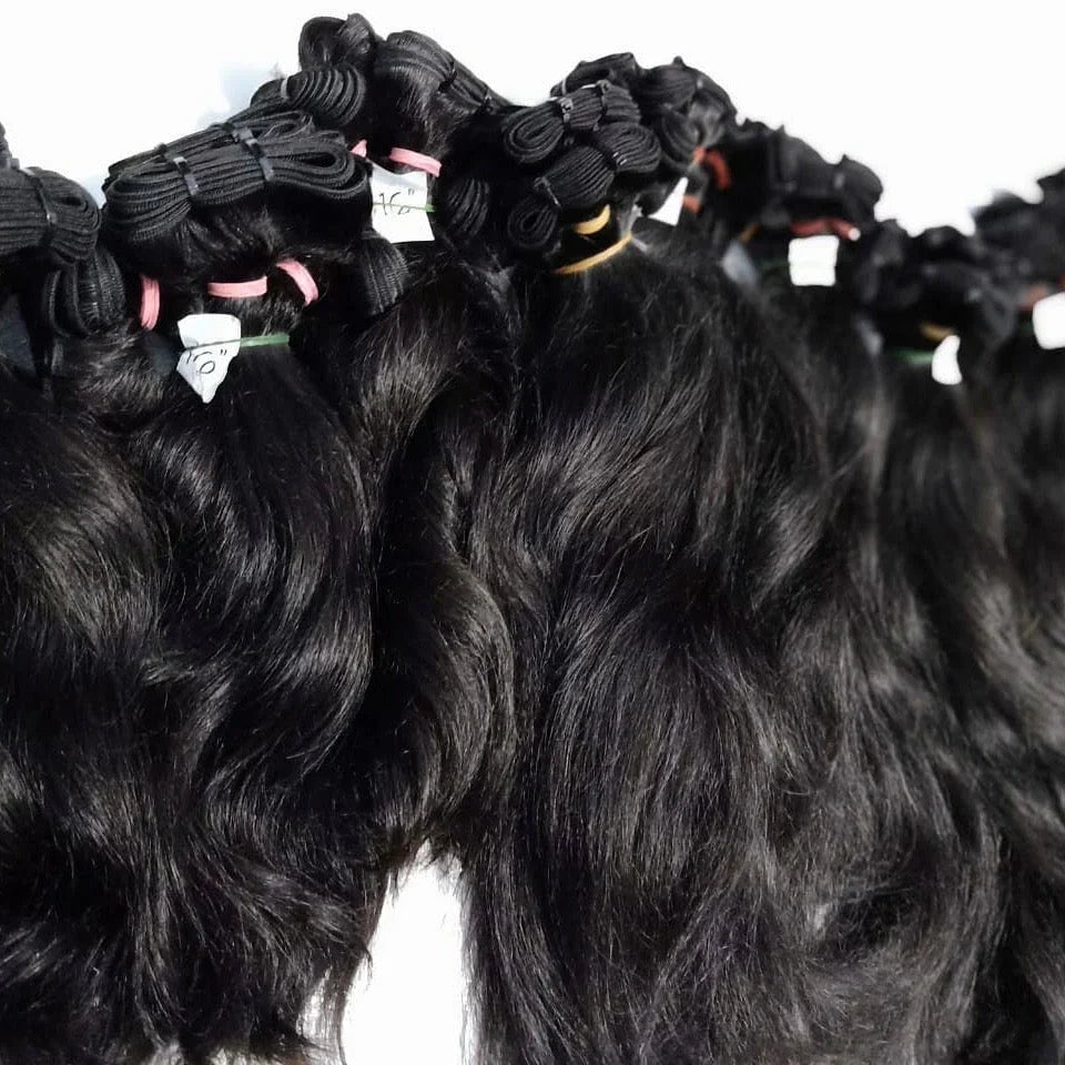 Bundles of premium wavy black hair extensions with size labels, arranged on a white background.
