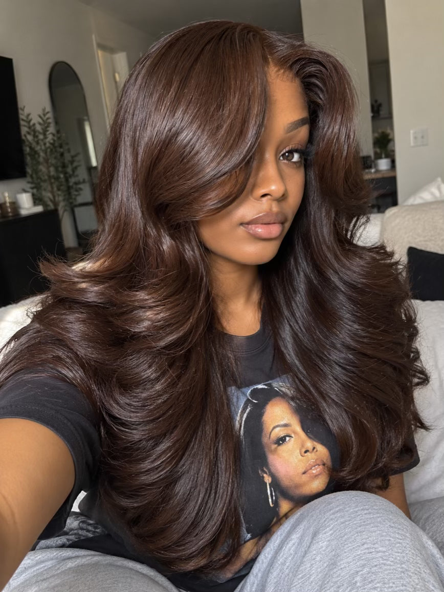 Woman wearing a 24 inch #2 dark brown body wave human hair wig with a 6x6 HD lace closure, styled in voluminous layers with a deep side-swept bang