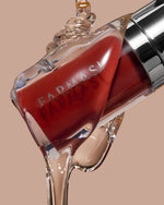 Farmasi liquid lipstick bottle with flowing glossy product on beige background