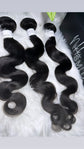 Three bundles of body wave human hair extensions on a white fur background